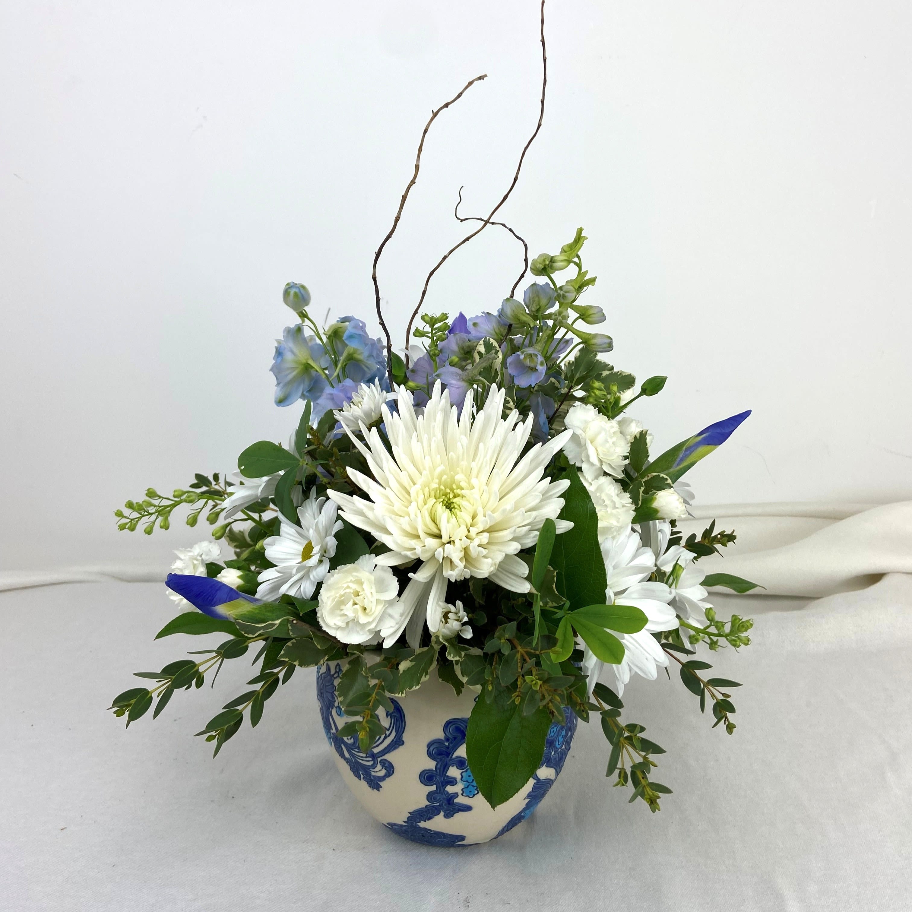 Paisley Blue  - White chrysanthemums, pale blue delphinium and daisies arranged in a rounded 5.5" paisley ceramic pot.