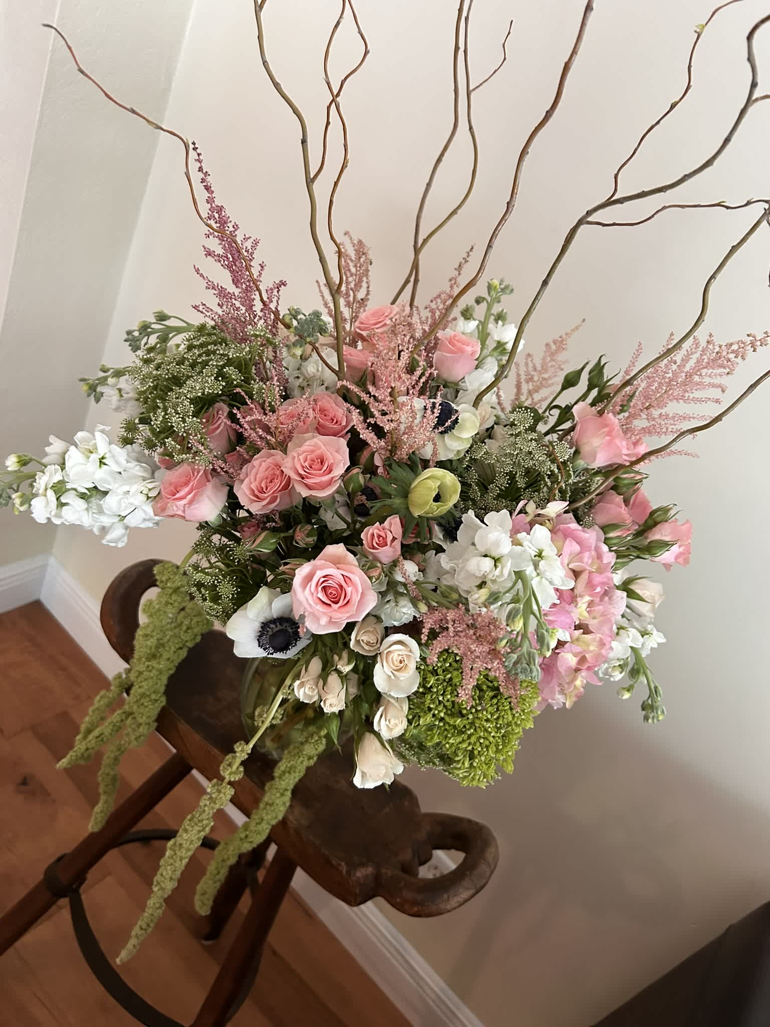 Large pink and white floral arrangement with tall branches in a vase