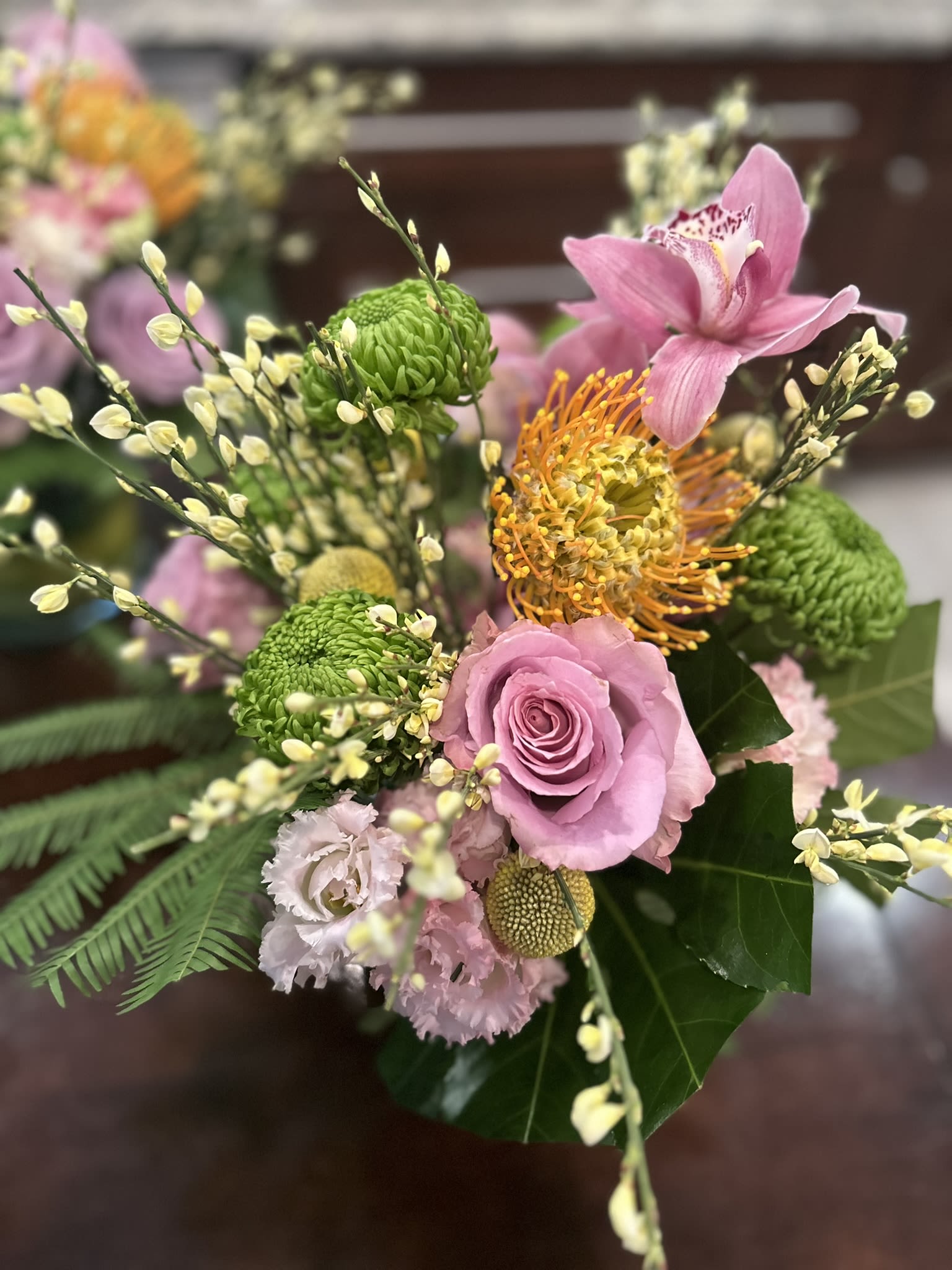 florist choice with exotics and roses (larger than shown) - Will be larger than shown12 roses and 2 orchids, plus accent pieces, such as pin cushions. as standard, deluxe and premium up to 2 dozen roses and multiple orchids and accent peices. 