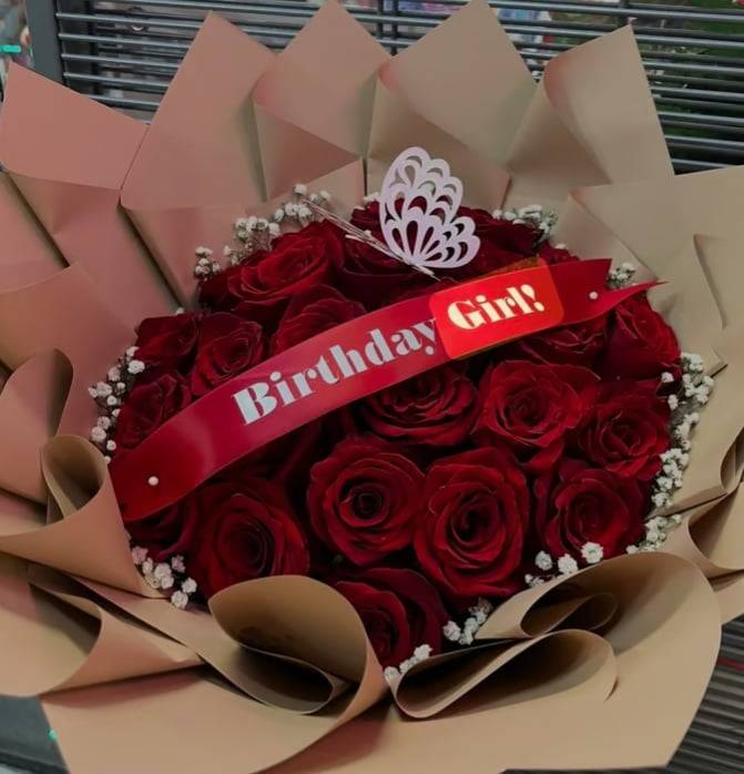 Bouquet of red roses wrapped in tan paper with a birthday ribbon