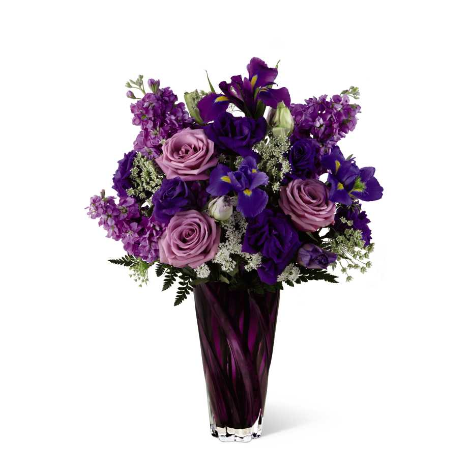 The FTD Casual Elegance Bouquet - The FTD Casual Elegance Bouquet colors Valentines Day passion in untraditional shades of purple to surprise and dazzle your sweetheart with a fresh and untraditional expression of love. Lavender roses, purple gilly flowers, purple double lisianthus, and purple irises are beautifully highlighted with white Queen Anne's Lace and lush greens in an heirloom quality vase of heavy, amethyst cut glass. Truly an elegant, beautiful way to celebrate romance.