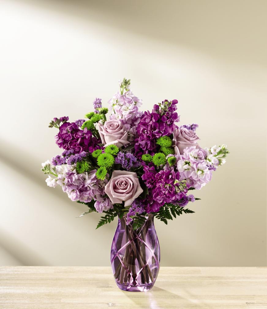 The FTD Sweet Devotion Bouquet by Better Homes and Gardens - Deluxe - FTDÂ¨ proudly presents the Better Homes and GardensÂ¨ Sweet DevotionÂª Bouquet. Purple is a shade that captivates the imagination and inspires, with it's fascinating cool shades of light and dark. Bringing together a collection of purple's finest blooms, this enchanting bouquet offers a combination of the swirling petals of lavender roses, the fragrant stalks of purple and lavender gilly flower, and purple statice accented with clusters of green button poms and lush greens. Arranged to perfection within an attractive keepsake purple glass vase, this gorgeous flower bouquet is ready to create a special Mother's Day, birthday, anniversary, or thinking of you moment! GOOD bouquet includes 9 stems. Approx. 15"H x 11"W. BETTER bouquet includes 14 stems. Approx. 16"H x 14"W. BEST bouquet includes 18 stems. Approx. 17"H x 15"W. EXQUISITE bouquet includes 24 stems. Approx. 18"H x 16"W.