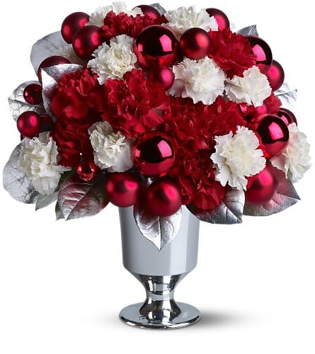 So Very Merry - Celebrate the holidays with this glamorous mix of ornaments, blooms and leaves in red, white and silver. Ruby-red Christmas ornaments and fresh red and white carnations nestle with silvery leaves in a silver-toned vase. A splendid way to send good wishes this year.    A mix of red and white carnations - accented with matte and shiny red ornament balls and silver-sprayed leaves - is delivered in a silver-toned pedestal vase.    Approximately 13" (W) x 14" (H)    Orientation: All-Around    As Shown : TFWEB464