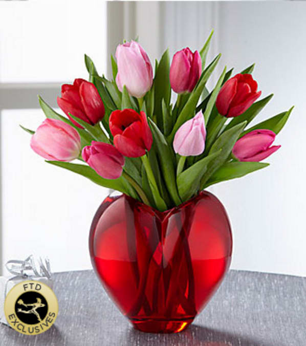 The FTD® Season of Love™ Bouquet - The FTD® Season of Love™ Bouquet takes a springtime approach to declaring your Valentine's Day love. Red and pink tulips make an early, out-of-season appearance simply and elegantly arranged in a sculptural, heart-shaped vase of vibrant, ruby-colored glass. What a way to sweep that special someone, off their feet! Your purchase includes a complimentary personalized gift message.