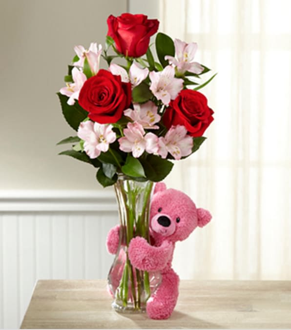 Hug Me Tender Valentine's Day Bouquet - VASE &amp; BEAR INCLUDED - Picked fresh from the farm and set to truly bring sweetness, romance, and light to their valentine celebration, our Hug Me Tender Valentine's Day Bouquet is set to send your love across the miles. Hand gathered at select floral farms and bringing together the blushing colors of the holiday, red and pink, this beautiful flower bouquet has been picked fresh for you to create that perfect Valentine's gift for friends, family, or your special someone this coming February 14th. Bouquet includes: red roses, pink Peruvian Lilies, and lush greens. Presented in a clear glass bud vase with a pink bear hugging at the neck.  GOOD bouquet is approx. 18"H x 19"W. BETTER bouquet is approx. 20"H x 10"W. BEST bouquet is approx. 21"H x 10"W. Your purchase includes a complimentary personalized gift message.