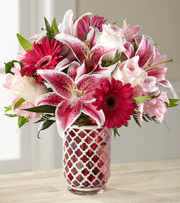 The Sweet Life Bouquet - VASE INCLUDED - Picked fresh from the farm to deliver a sweet expression of love and affection to your special recipient, The Sweet Life Bouquet, has a sophisticated appeal they will love. Hand gathered at select floral farms and bringing together a selection of varied blushing blooms blossoming with eye-catching color and texture, this bouquet has been picked fresh for you to help you celebrate a birthday, an anniversary, Valentine's Day, or as a way to say, "I love you." Bouquet includes: Stargazer Lilies, pale pink roses, deep pink gerbera daisies, light pink Peruvian Lilies, and lush greens. Presented with a Moroccan pink mosaic hurricane vase. Bouquet is approximately 14" H X 13" W Your purchase includes a complimentary personalized gift message.