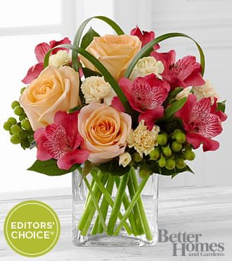 The FTD® All Aglow™ Bouquet by Better Homes and Gardens® - VASE INCLUDED - C15-4950D  FTD® proudly presents the Better Homes and Gardens® All Aglow™ Bouquet. Light up their life with incredible color and blooming beauty when you send this exquisite flower bouquet. Unforgettable peach roses are surrounded by red Peruvian lilies, pale yellow mini carnations, green hypericum berries, lily grass blades, and lush greens to create a stunning flower arrangement. Presented in a clear glass cube vase to give it a sophisticated look, this mixed flower bouquet will express your sweetest thank you, get well, or congratulations wishes.  BETTER bouquet is approximately 9"H x 10"W.