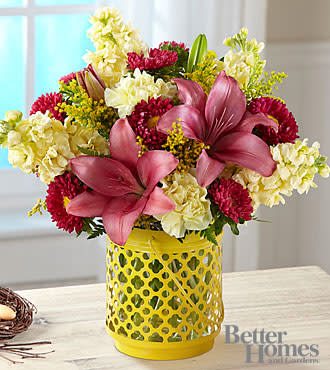 The FTD® Arboretum™ Bouquet by Better Homes and Gardens® - HG7S  A tabletop botanical garden perfectly scaled for making anyone's day bloom with color, joy and excitement. Designed in collaboration with the stylists of Better Homes and Gardens® this happy-making four-season arrangement combines sunny yellow carnations and stock blossoms with contrasting pink Matsumoto asters and Asiatic lilies. The lantern style vase features a clear glass cylinder in a metal cut out holder painted brilliant yellow to complement the color of the flowers. Once the flowers are gone, the vase makes an enchanting candleholder for use indoors and outside. 