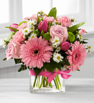 The FTD® Blooming Visions™ Bouquet by Better Homes and Gardens - B29-4805E  FTD® proudly presents the Better Homes and Gardens® Blooming Vision™ Bouquet. Offer them a bouquet blooming with a "fresh from the garden" appeal. Pink roses, hot pink tulips, pink mini carnations and pink gerbera daisies are accented with white Monte Casino asters and lush greens. Gorgeously arranged in a clear glass cube vase accented with a pink satin ribbon, this bouquet is a soft and graceful way to send your warmest sentiments.