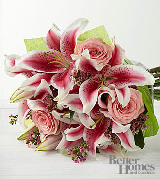 The FTD® Simple Perfection® Bouquet by Better Homes and Gardens ® - Hand Tied - B25-4390H  FTD® presents the Better Homes and Gardens® Simple Perfection™ Bouquet. Speak from your heart to theirs with a collection of pink vibrant blooms. Pale pink roses collaborate with the magic of Stargazer Lilies, displaying their fragrant fuchsia petals amidst waxflower accents. Beautifully arranged, this Hand-Tied bouquet sends your warmest sentiments with glamour and grace. HAND-TIED bouquet is approximately 13" in diameter. Lilies may arrive in various stages of development. The lily blooms will continue to open, extending arrangement life - and your recipient's enjoyment.