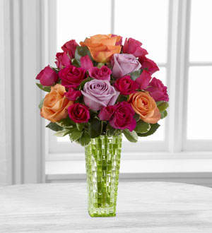 The FTD® Sun’s Sweetness™ Rose Bouquet by Better Homes and Gardens® - BWR  FTD® proudly presents the Better Homes and Gardens® Sun’s Sweetness™ Rose Bouquet. Displaying a collection of sunset hues, this rose bouquet is a wonderful way to delight your special recipient. Orange roses, lavender roses and hot pink spray roses are beautifully arranged amongst lush greens to create a flower bouquet that will capture their every attention. Presented in a designer green glass vase, this flower arrangement is the perfect way to say happy birthday, offer your congratulations or convey your heartfelt message of love and affection.