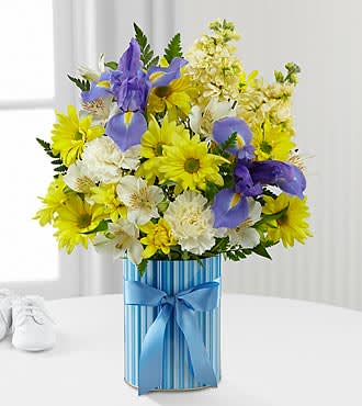 The FTD® Little Miracle™ Bouquet – Boy - LMBS  The FTD® Little Miracle™ Bouquet is the perfect way to welcome the newborn into the world and help the family celebrate on this most momentous occasion! Bringing together pale yellow carnations, blue iris, white Peruvian Lilies, yellow traditional daisies, fragrant pale yellow stock and lush greens, this stunning flower bouquet exudes warm wishes and sunlit cheer. Presented in a designer striped blue container accented with a satin blue ribbon on the front, this beautiful mixed flower arrangement will be a memorable gift for the new family.