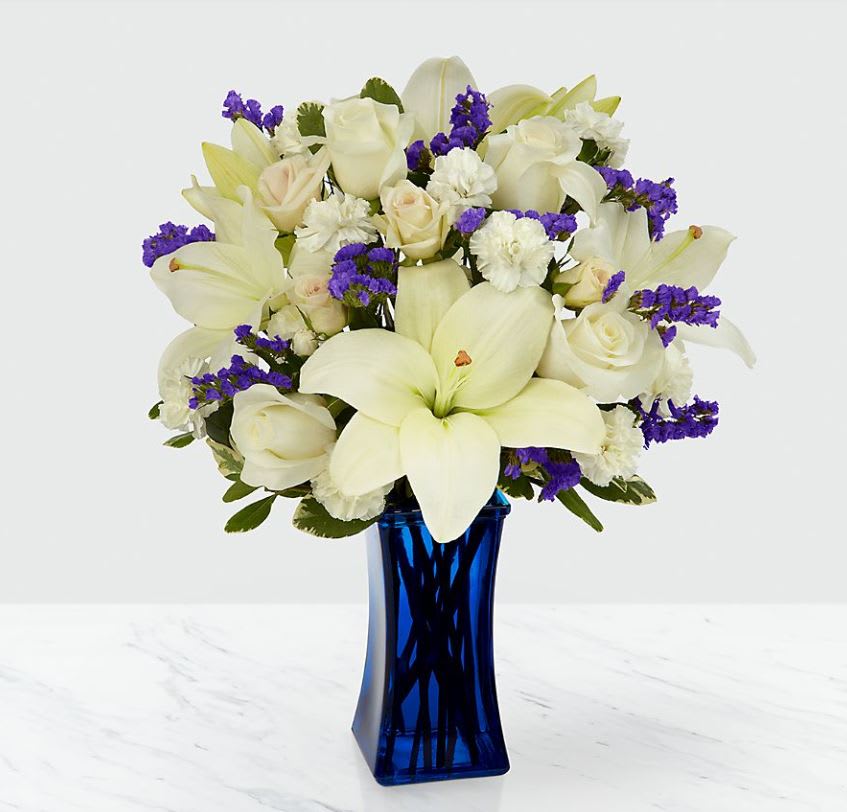 Beyond Blu Bouquet - Our Beyond Blue Bouquet features lilies, roses, carnations and lush greens to captivate your recipient. A collection of brilliant white blooms is contrasted by a stunning and bold blue vase. This arrangement makes an excellent thank you, get well or engagement gift! For sharing your sympathies, this bouquet is best fit to send to a home or residence.