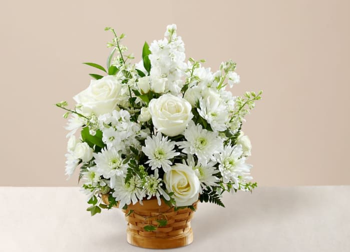 Heartfelt Condolences Arrangement - Let this exquisite composition of beautiful white blossoms deliver your sympathy and comfort loved ones grieving a loss. The elegance of this arrangement and its warm, homey basket base makes it an appropriate addition to any wake, funeral or graveside service, or to send to the home of family or friends. Handcrafted by a local FTD artisan florist of individually selected white roses, stock, cushion pompons and larkspur set among complementary greens for a memorable bouquet that evokes a tranquil sense of heavenly hope.