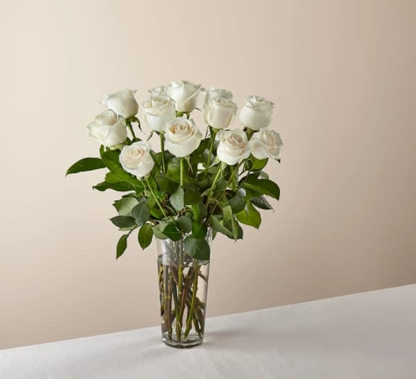 Long Stem White Rose Bouquet - White roses are elegant, luminous, and beautifully accent any room. With a gorgeous selection of crisp white roses among fresh greenery, this bouquet is perfect for birthdays, anniversaries, or as a way to say, "I'm thinking of you."  The Original Bouquet is approximately 20"H x 15"W.