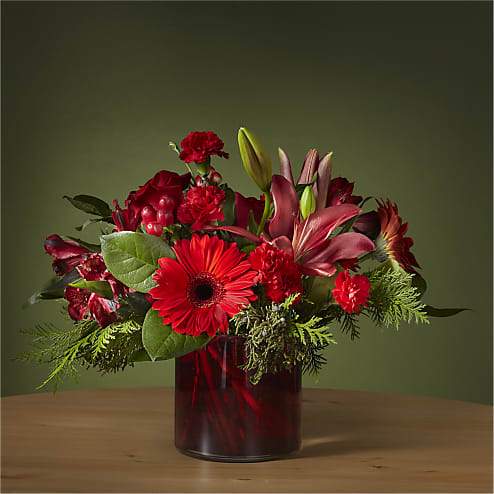 Berry Merry Bouquet - Add a touch of sophistication with the jewel tones of the Berry Merry Bouquet. This dynamic arrangement brings new life to classic stems while gerbera daisies and carnations showcase a rich red palette fit for the holiday.
