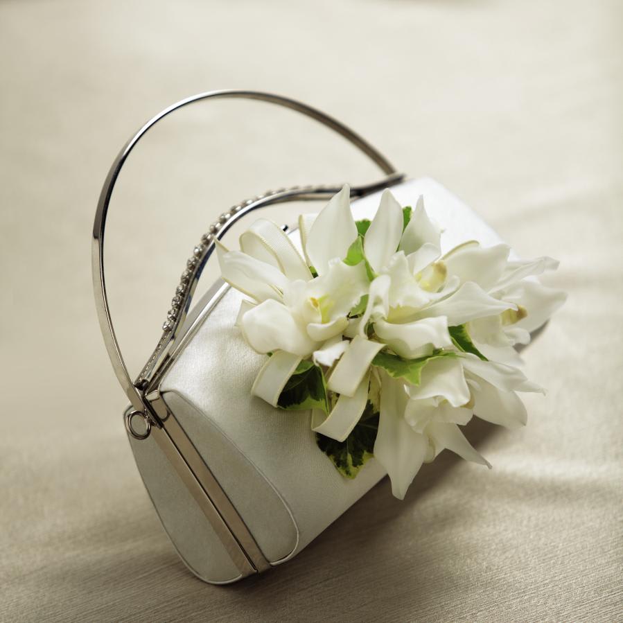FTD White Purse Decor - The FTD White Purse DÃ©cor turns your simple wedding clutch into a   memorable accessory. Mini Cymbidium Orchid stems are arranged with   variegated ivy vines and accented with an ivory taffeta ribbon to create   a wonderful way to add that extra touch to your wedding day. Approx.   4âH x 6'W. 