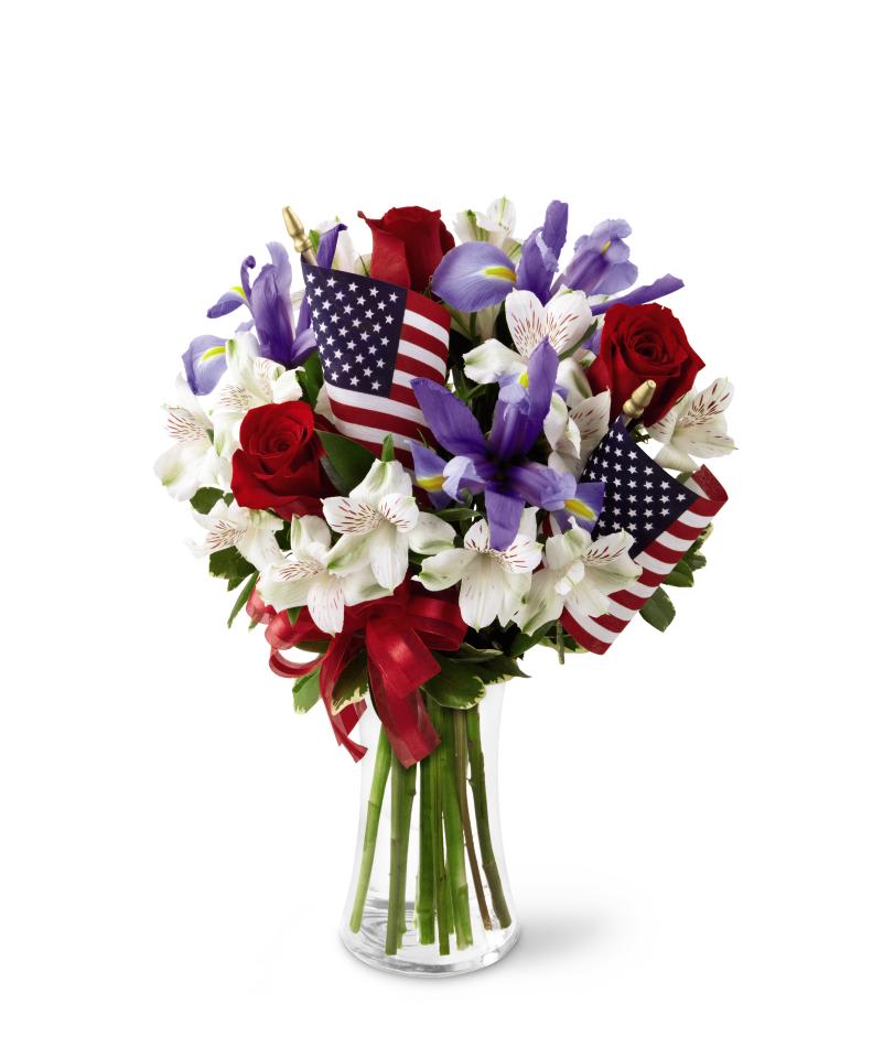 FTD Unity Bouquet - The FTD Unity Bouquet sparks the hearts of all Americans with its   patriotic beauty and dazzling color. Bright red roses mingle with blue   iris arranged amongst white Peruvian lilies and assorted greens.   Accented with two American Flags and a red, white and blue ribbon, this   stunning bouquet arrives arranged in a clear glass vase to create a   gorgeous way to celebrate our Independence Day. 18h x 14w  