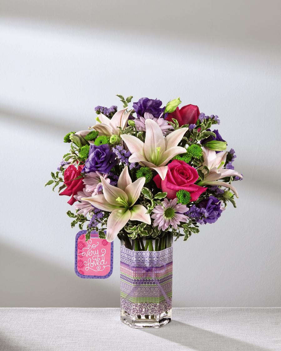 The FTD So Very Loved Bouquet by Hallmark - Deluxe - Mother's Day is a time to celebrate all of the amazing women in your days and let them know that they are loved for not only who they are, but how they have shaped and molded your life. The FTDÂ¨ So Very LovedÂª Bouquet by Hallmark is the perfect way to send this love straight to their door, bringing together hot pink roses, lavender daisies, pink Asiatic Lilies, purple double lisianthus, green button poms, and lavender statice to create a full and vibrant display. Presented in a keepsake clear glass vase with a purple, pink and green striped design at the center, this bouquet arrives with a Hallmark tag that reads, "So very loved," on one side and, "You are simply the best," on the on the other. The Mother's Day gift you have been searching for! GOOD bouquet includes 9 stems. Approx. 16"H x 11"W. BETTER bouquet includes 12 stems. Approx. 17"H x 13"W. BEST bouquet includes 18 stems. Approx. 18"H x 14"W. EXQUISITE bouquet includes 24 stems. Approx. 18"H x 15"W.