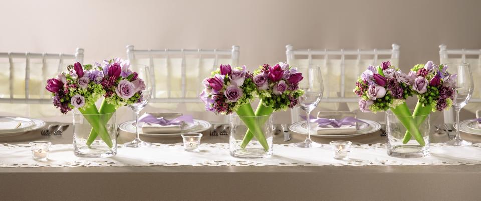 FTD Sublime Centerpiece - The FTD Sublime Centerpiece is a presentation of modern grace and   elegance. Two clear glass cylinder vases sit side-by-side holding two   bouquets in each, set in a diagonal direction for a fresh and sweet   look. Each bouquet consists of lavender sweet pea, purple tulips,   lavender spray roses, green mini hydrangea, purple lilac, purple   waxflower, green hypericum berries and lush greens set in a bright green   bouquet cone to give your wedding decor a look of refined   sophistication.  Each arrangement is approx. 12H x 6W.   