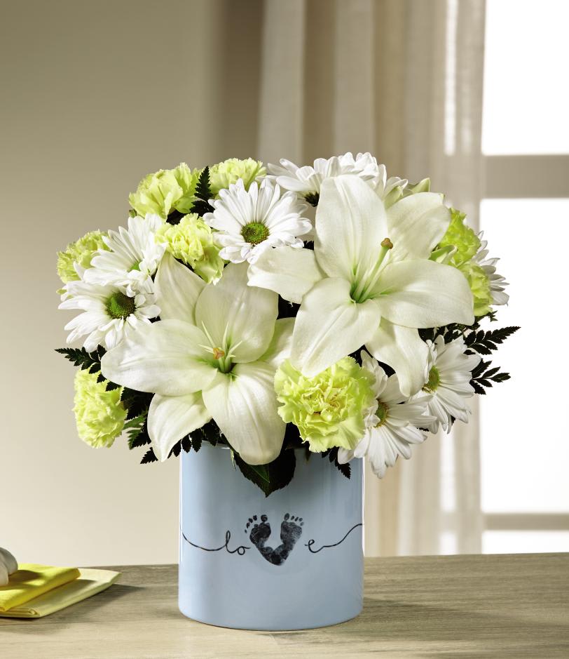 The FTD Tiny Miracle New Baby Boy Bouquet - The FTDÂ¨ Tiny MiracleÂª New Baby Boy Bouquet is the perfect way to send your happy wishes to the new family! Blooming with warmth and sunlight, this gorgeous flower bouquet brings together yellow roses, yellow carnations, yellow mini carnations, white Asiatic Lilies, and white traditional daisies to create a memorable gift. Presented in a keepsake blue ceramic vase with "Love" written in a script font on the front, and the print of a baby's foot making up the 'V' in the word for a sweet and touching affect, this fresh flower arrangement is a wonderful way to send your congratulations to friends and family at this joyful time in their lives. GOOD bouquet includes 10 stems. Approx. 11"H x 10"W. BETTER bouquet includes 14 stems. Approx. 12"H x 10"W. BEST bouquet includes 18 stems. Approx. 13"H x 11"W. EXQUISITE bouquet includes 20 stems. Approx. 13"H x 12"W.