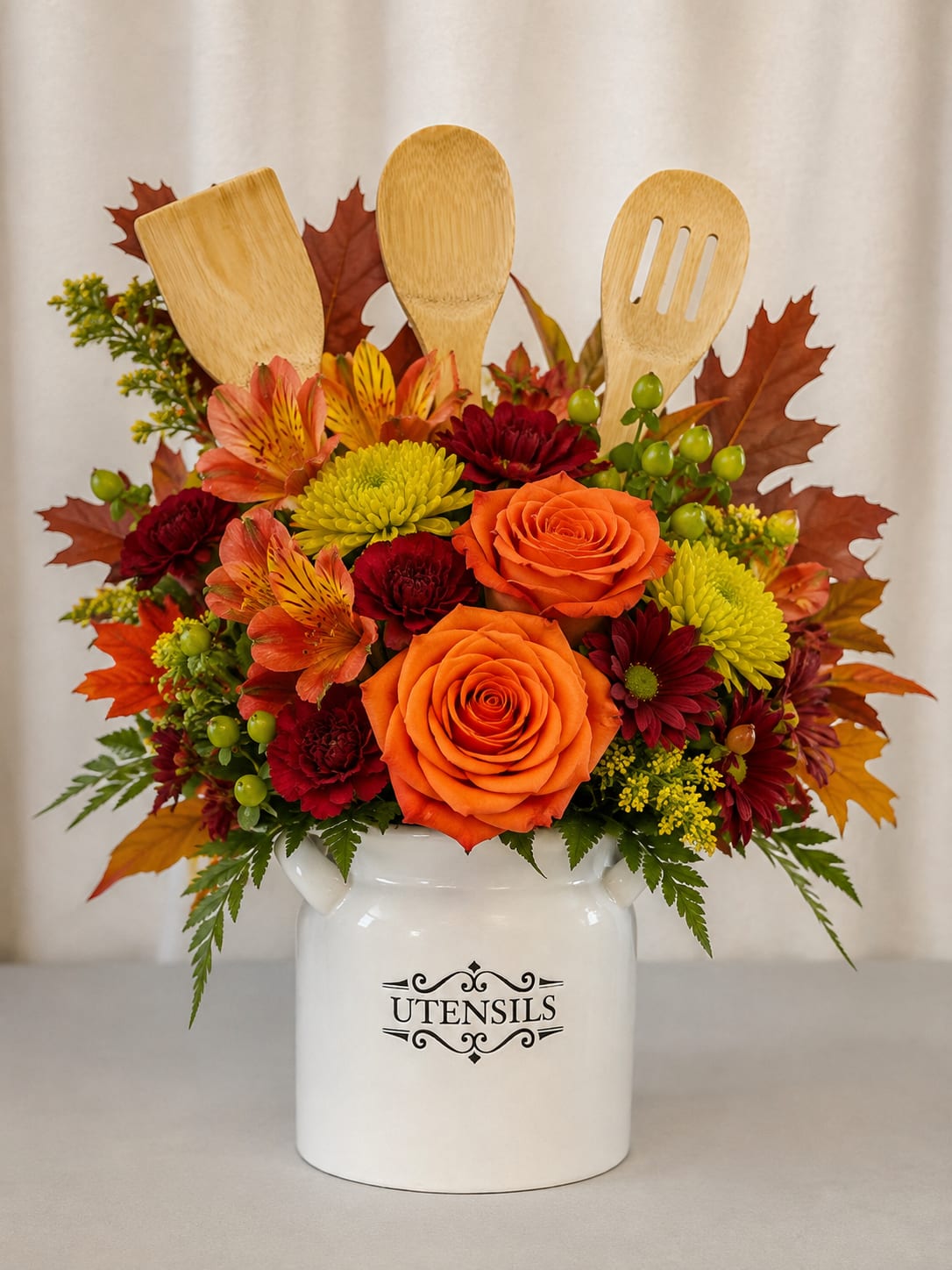 Autumn floral arrangement in a white utensil holder with wooden kitchen tools