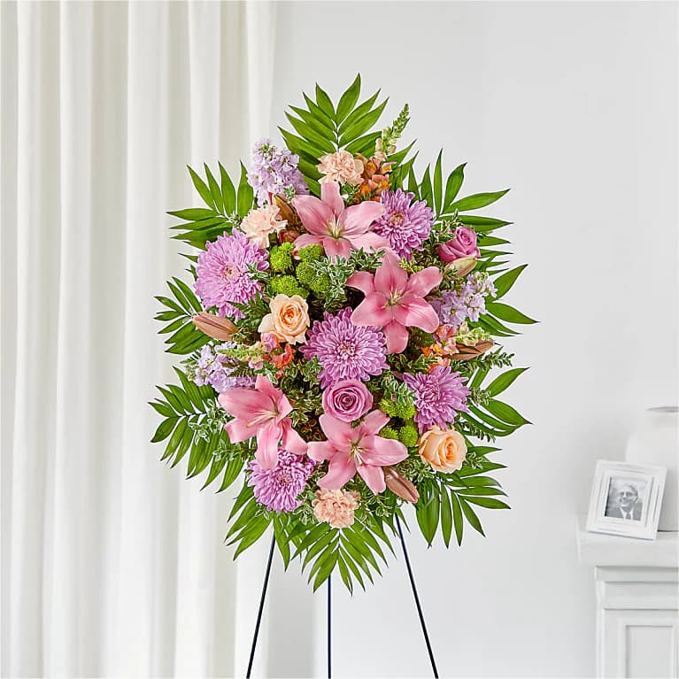 Standing floral spray with pink lilies, roses, and purple mums on an easel