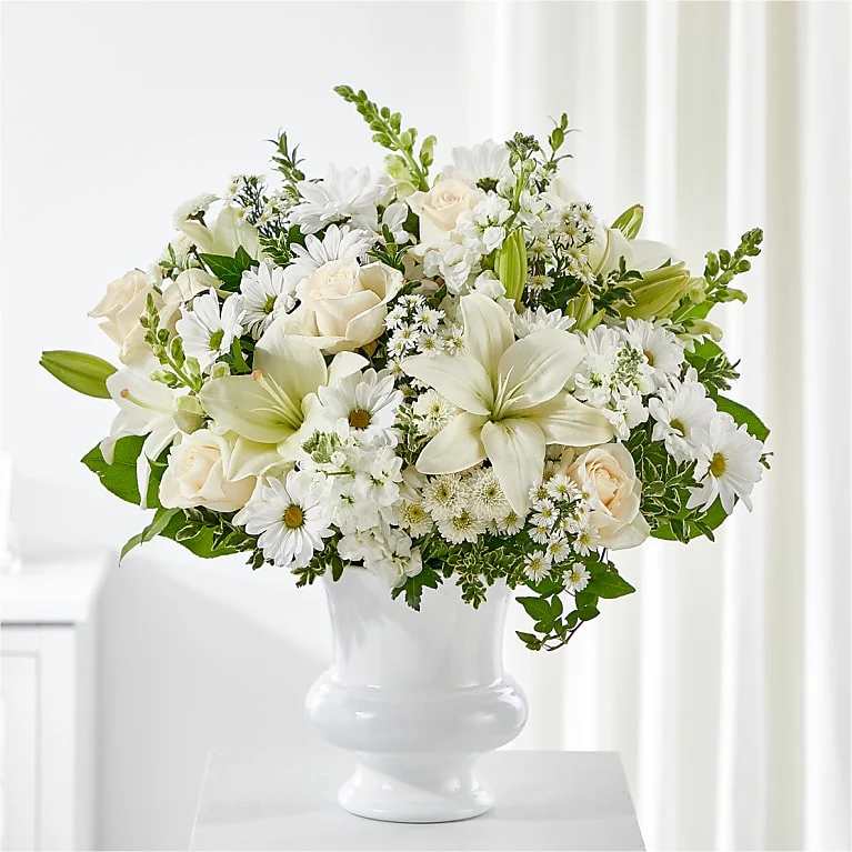 White floral arrangement in a white vase with roses and lilies