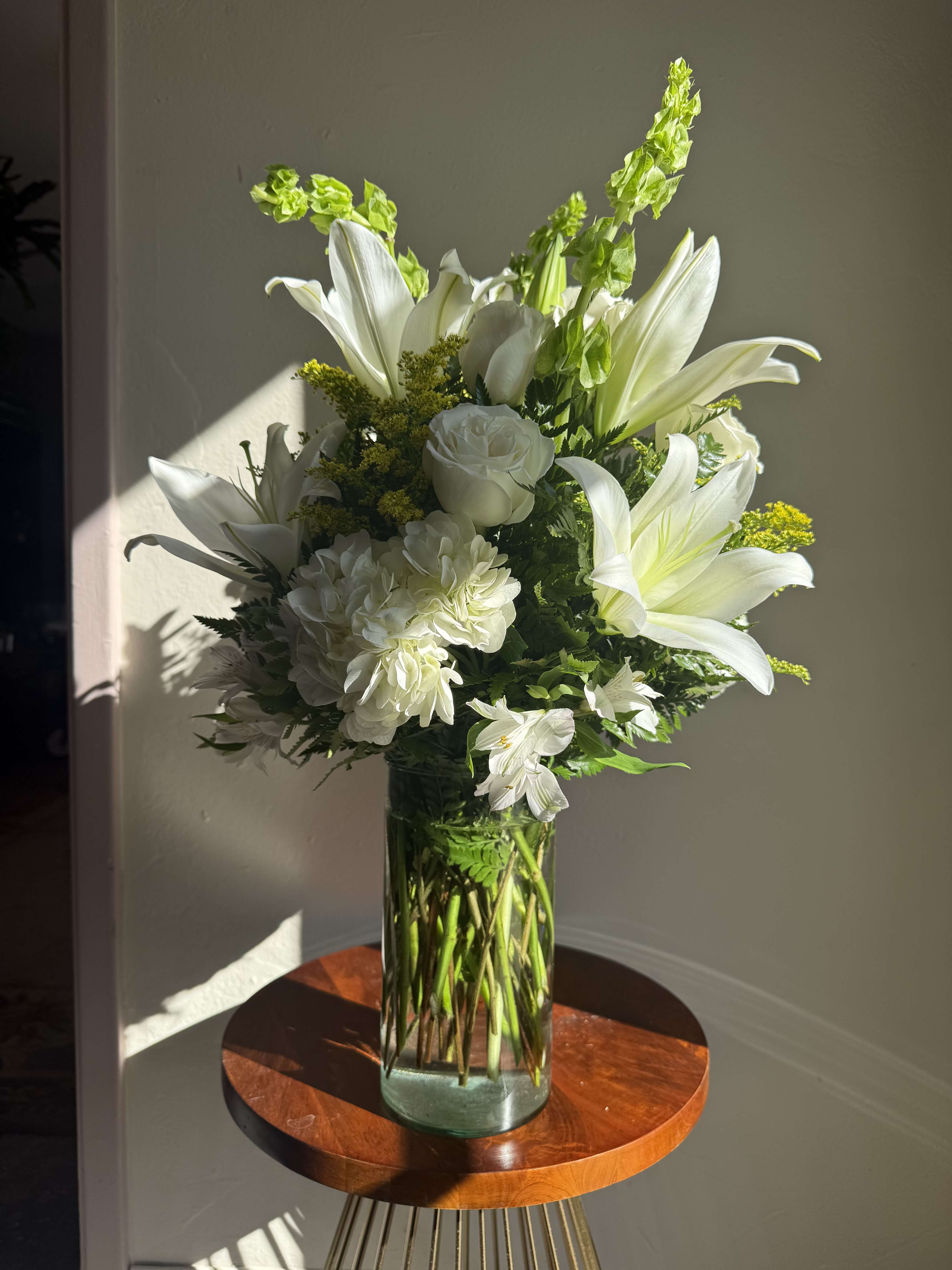 White lilies and roses arranged in a clear glass vase