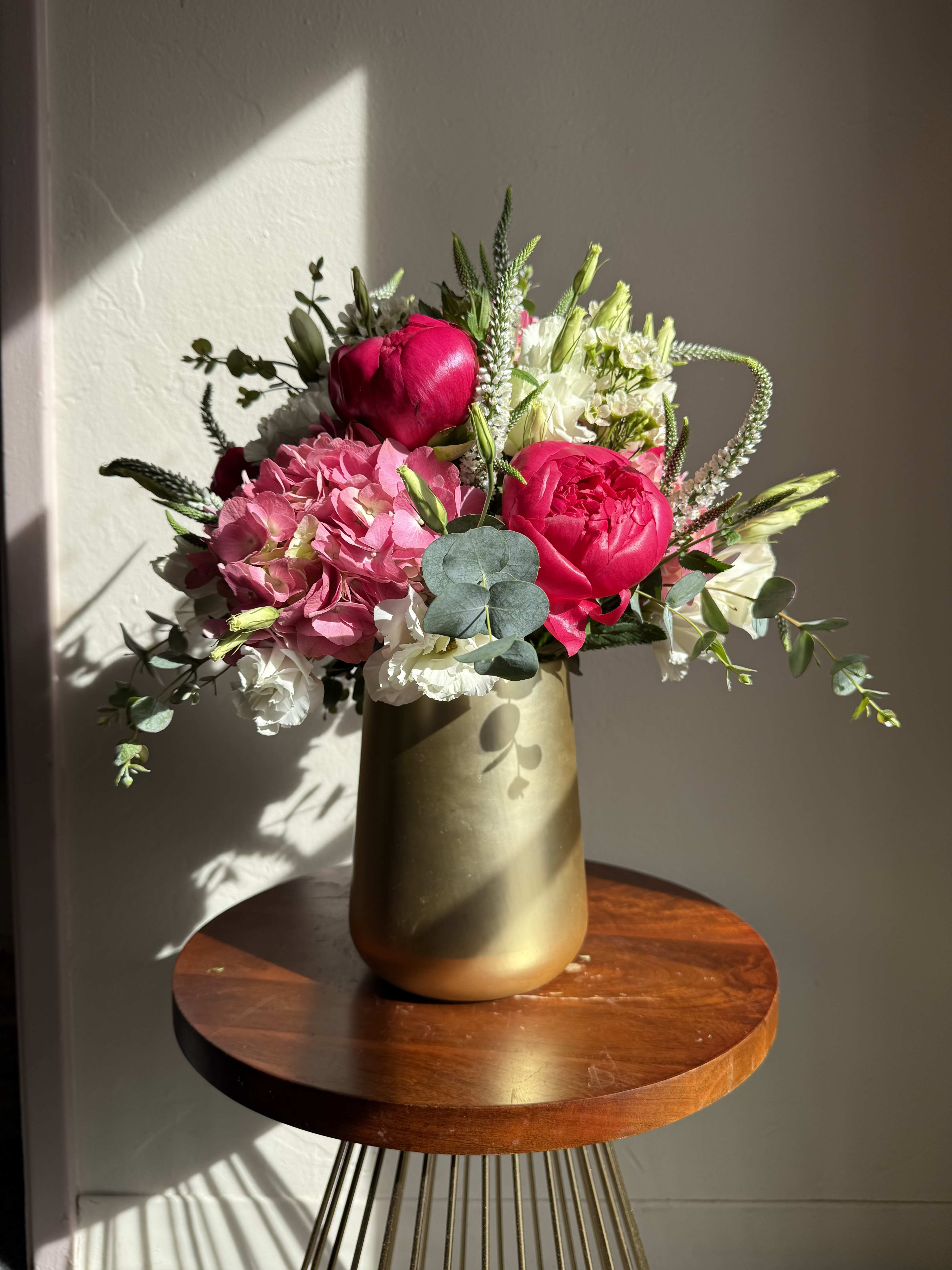 Pink and white floral arrangement in a gold vase