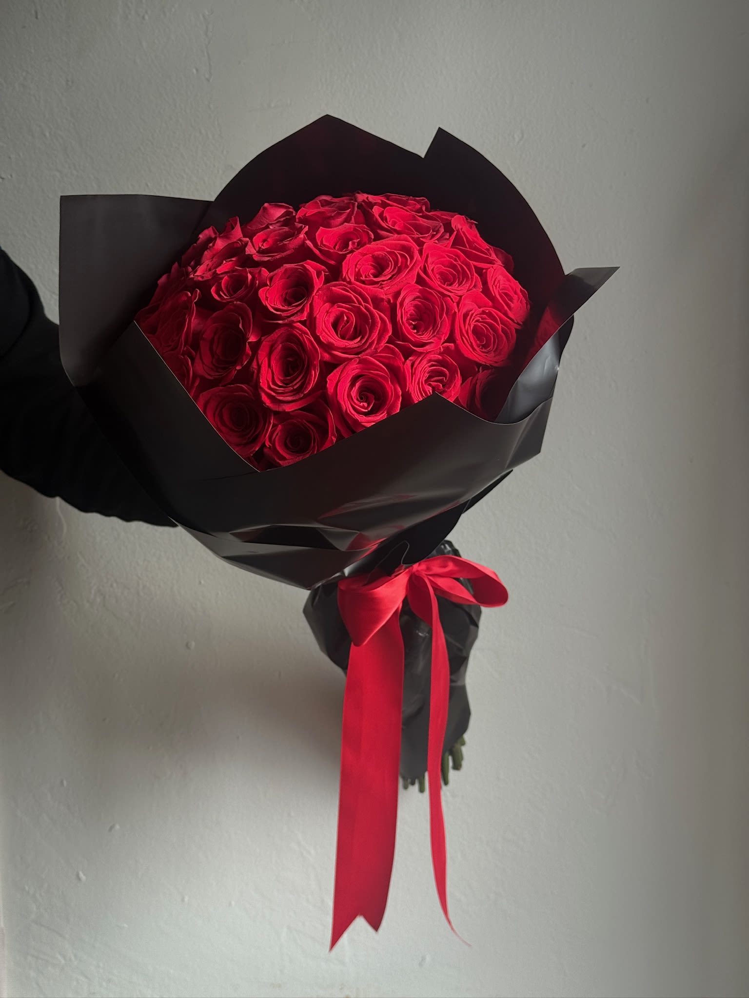 Bouquet of red roses wrapped in black paper with a red ribbon