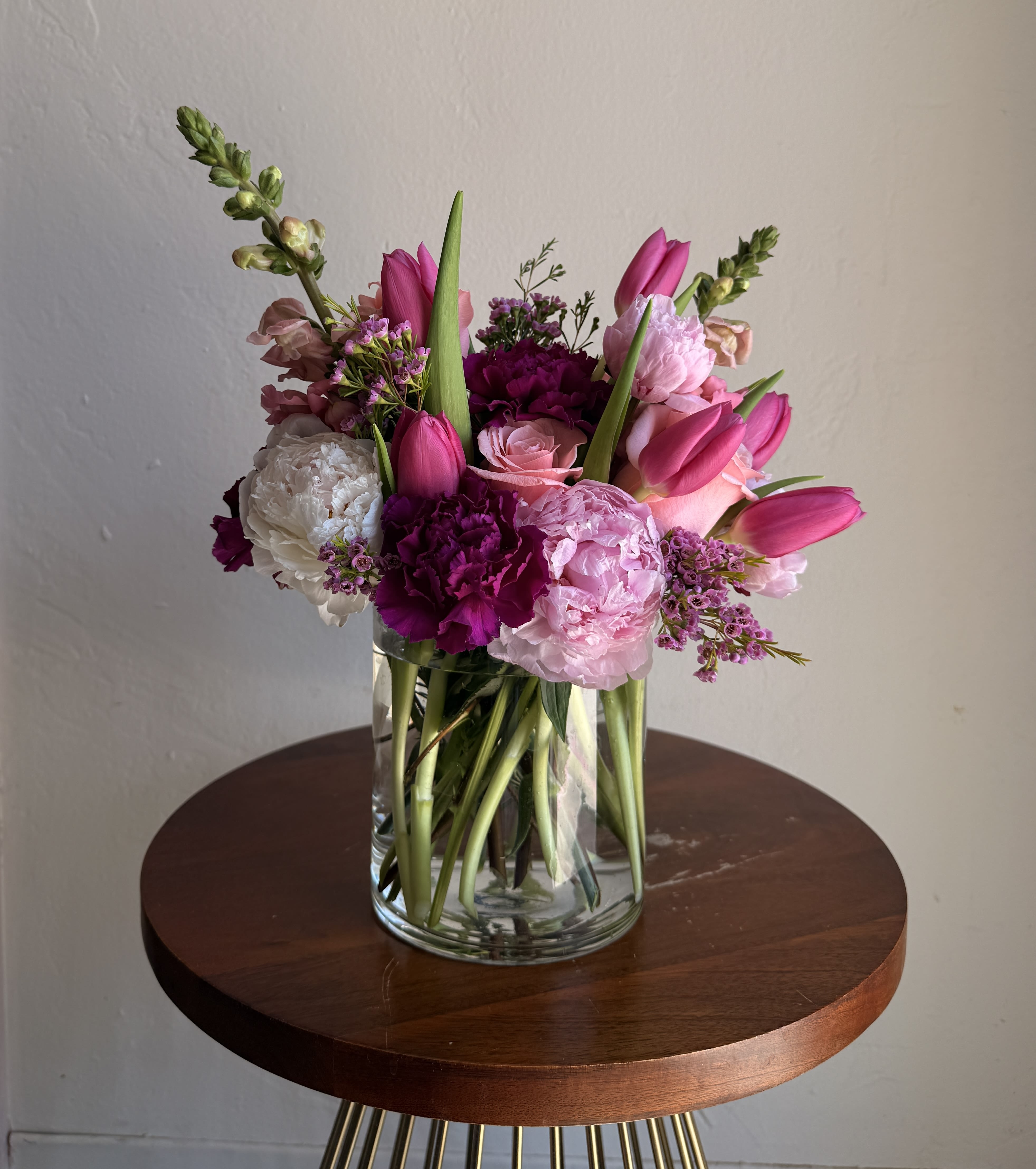 Peonies &amp; Co. - A lively garden-style bouquet in pinks, blush, white and soft purples that reads as both romantic and cheerful-perfect as a birthday bouquet, anniversary flowers, or a thoughtful Mother's Day gift. Tulips arch above a dense cluster of carnations, roses and snapdragons, giving the arrangement height and a fresh, slightly asymmetrical silhouette that still feels beautifully composed for love and romance or a simple "just because" surprise.