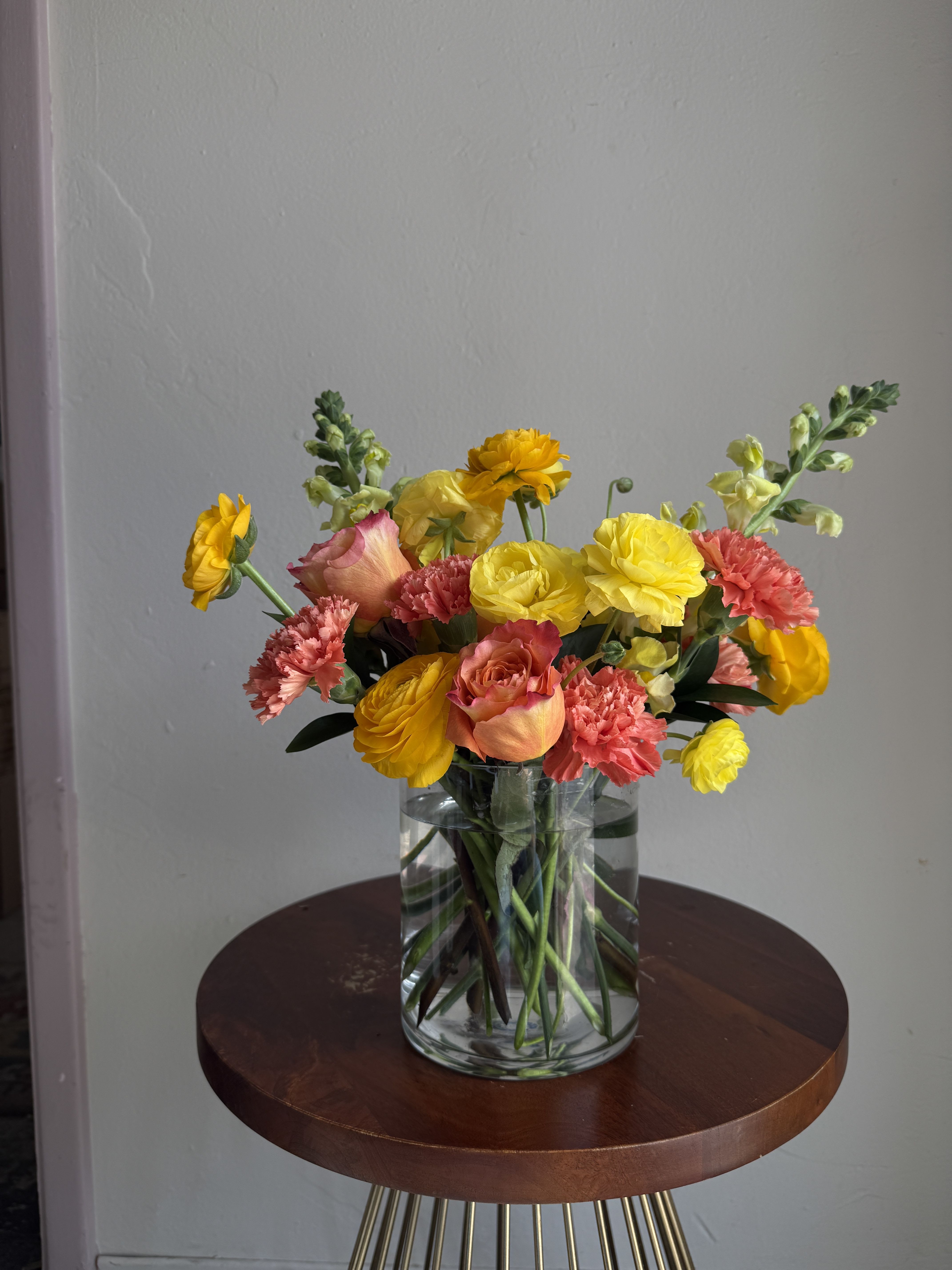 Summertime Blooms - a variety of blooms including ranunculus, roses and carnations in a bright summetime color palette showing yellow and orange hues