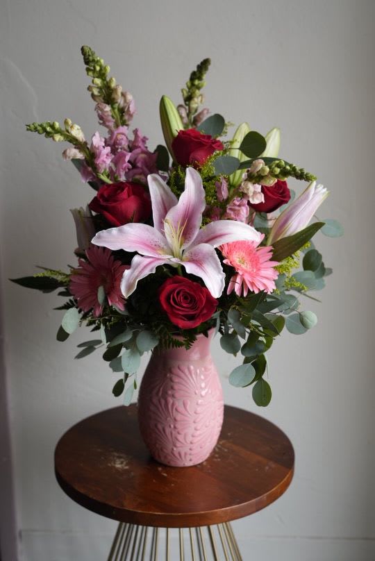 Roots of Mexico Pink Vase - Designers Choice - Pink Specialty Vase, handcrafted in Mexico. Mix of seasonal flowers with lush florals which may include roses, spray roses, gerbera daisies, lilies and hydrangeas arranged in a vase. Colors and flowers will be based on the designers choice, selecting the freshest blooms available. 