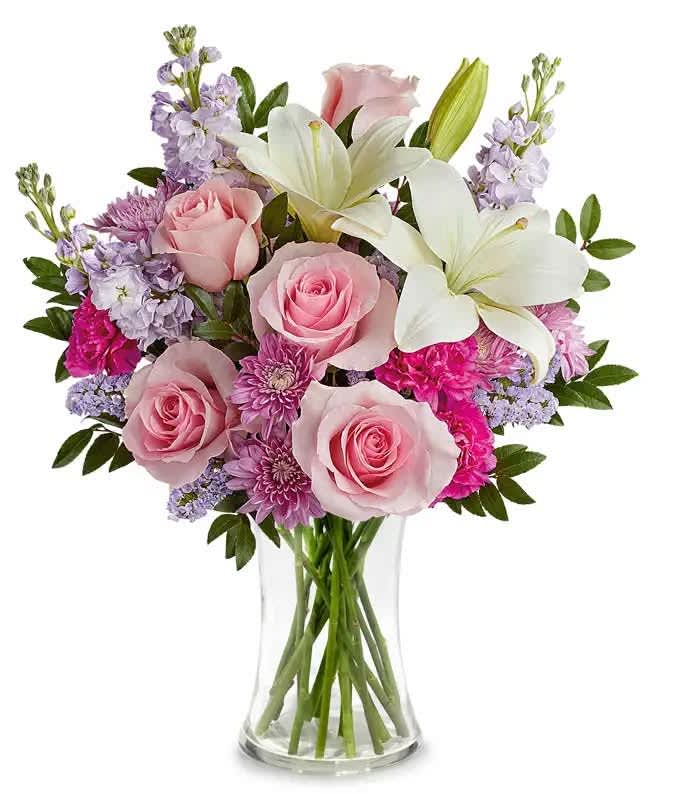 Pink roses and white lilies in a clear glass vase
