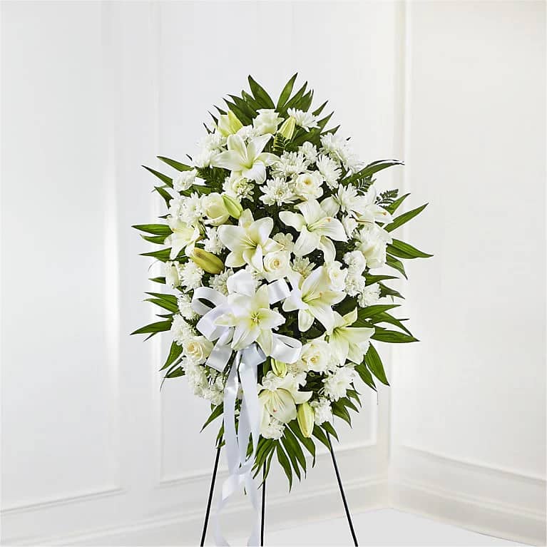 White floral standing spray on an easel with a ribbon