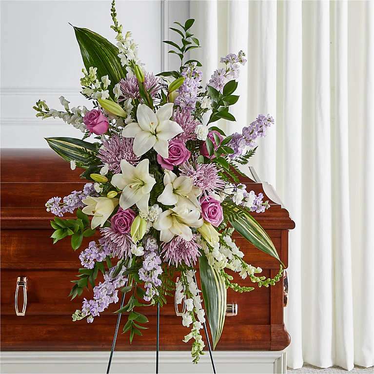 Standing funeral spray with white lilies, pink roses, and lavender flowers