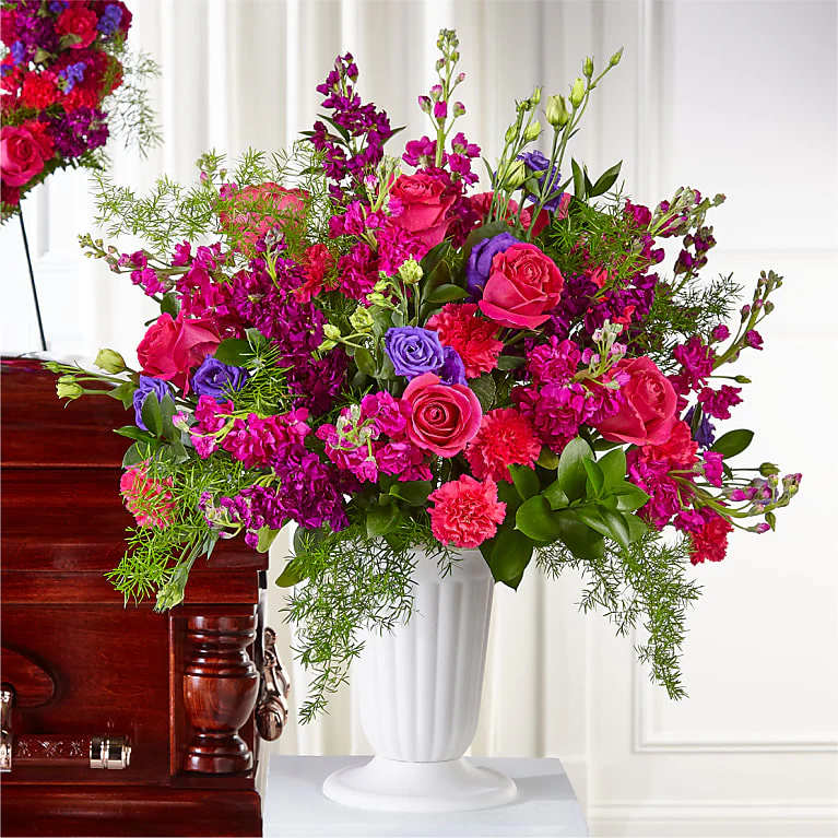 Large bouquet of pink and purple flowers in a white pedestal vase