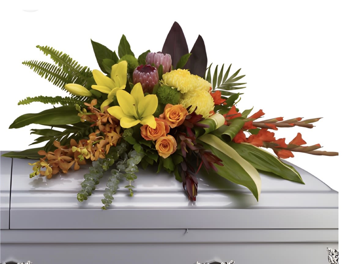 Tropical floral spray with yellow lilies and orange roses on a casket