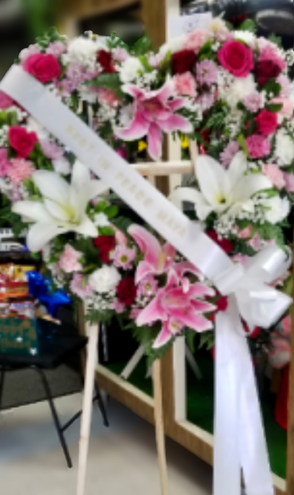 Two pink and white floral wreaths on easels with white ribbons