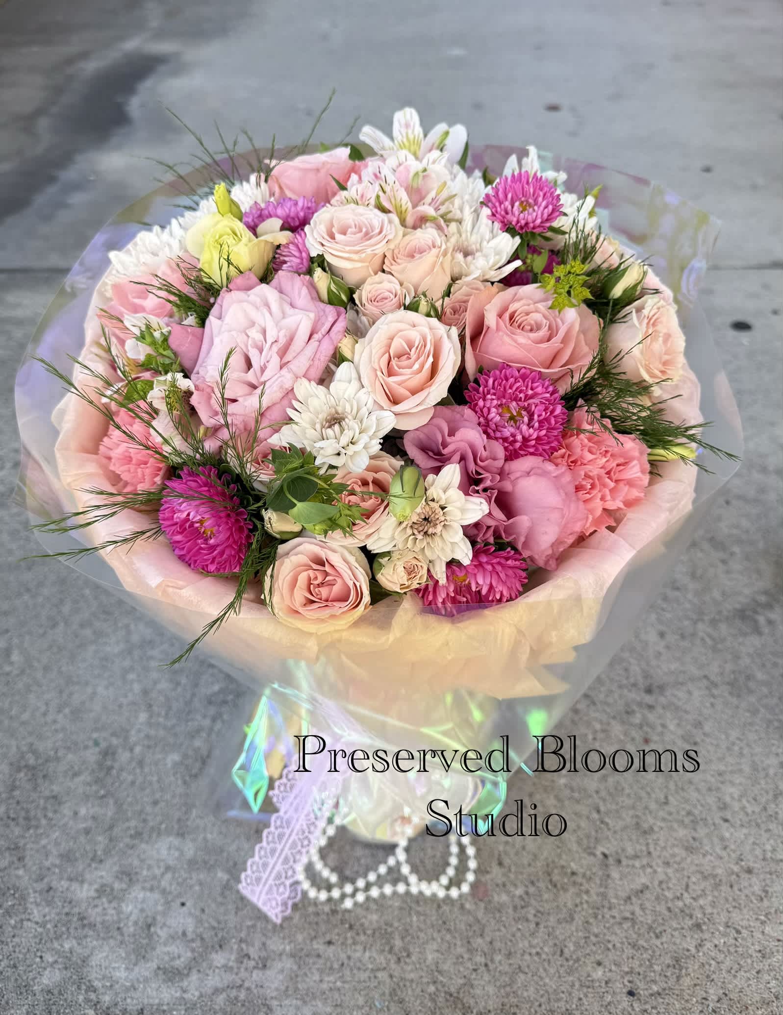 Bouquet of pink and white roses with mixed blooms wrapped in pastel paper