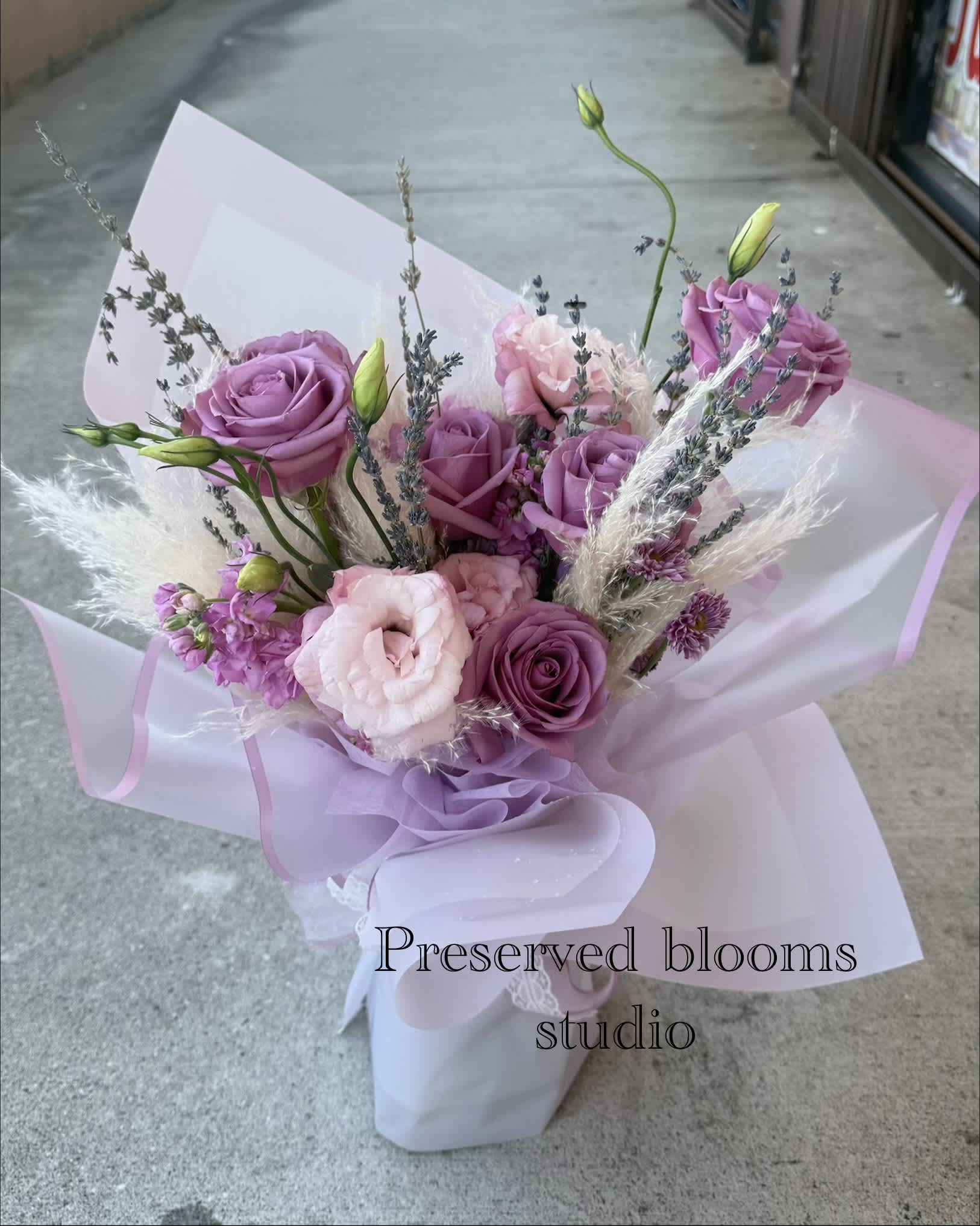 Lavender and pink bouquet of roses and lisianthus wrapped in pale paper