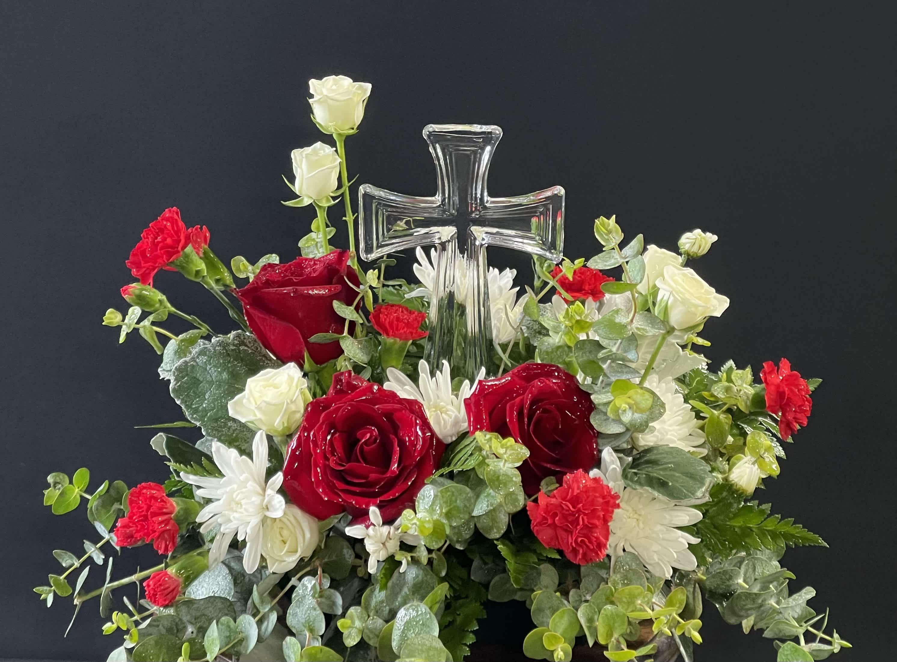 Red and white floral arrangement with a clear glass cross centerpiece