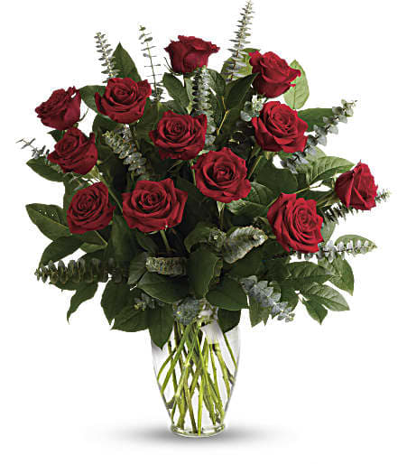 Red roses arranged in a clear glass vase with greenery