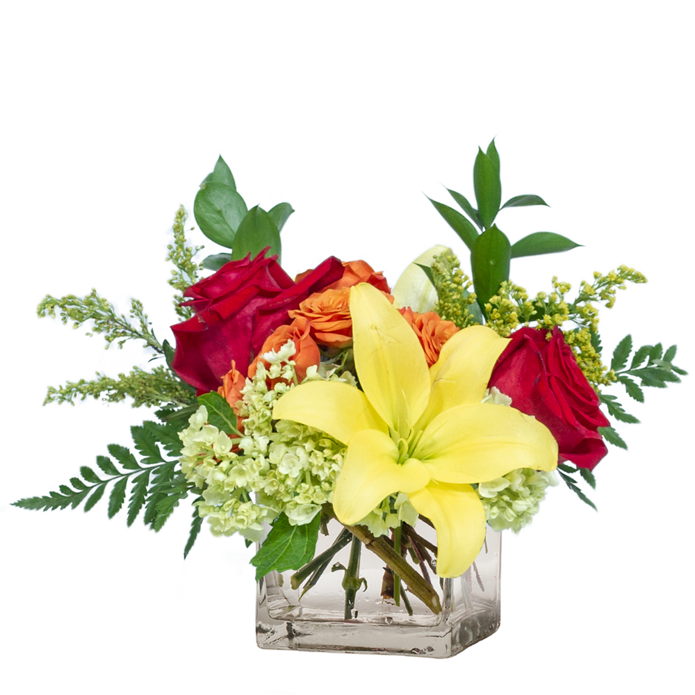 Bouquet of red roses, yellow lilies, and orange flowers in a clear glass vase