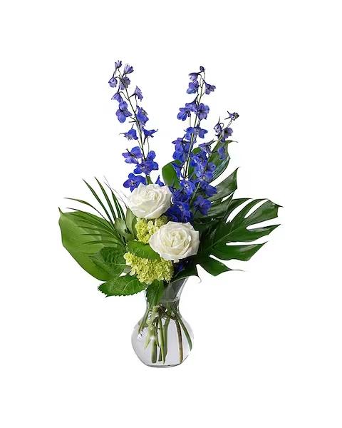 White roses and blue flowers in a glass vase