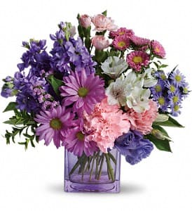 Mixed purple and pink flowers in a purple glass vase