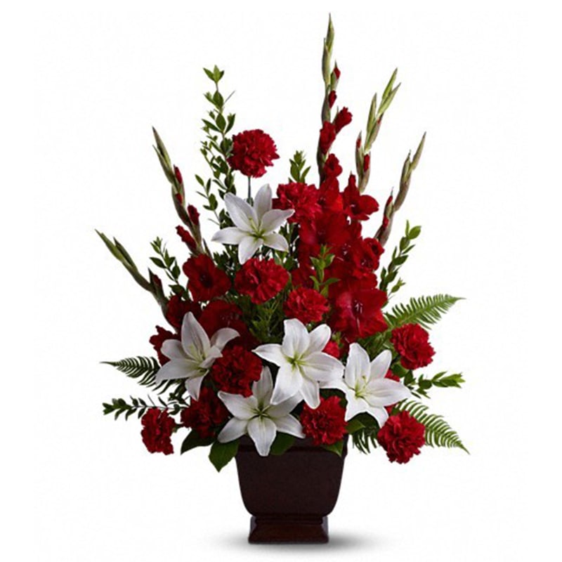 Red carnations and white lilies in a dark vase