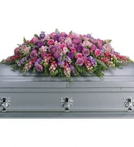 Pink and purple floral casket spray on a gray casket