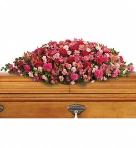 Pink and red floral spray on a wooden casket